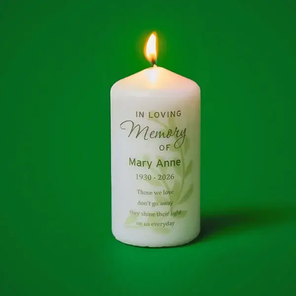 Personalised memorial candle with an In Loving Memory message, displayed lit against a green background.